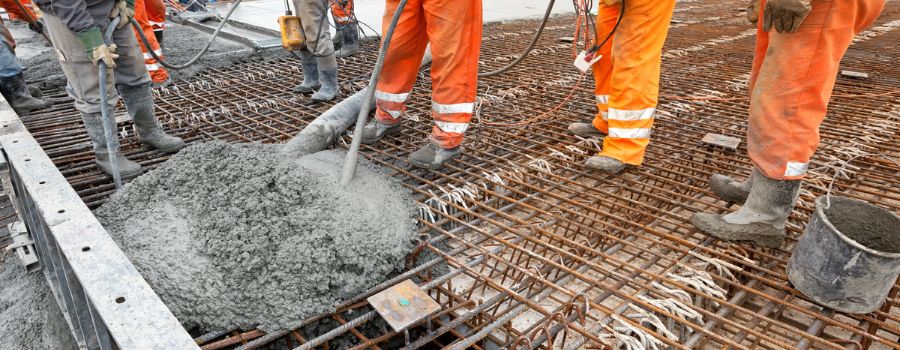 Construction workers pouring wet concrete using concrete bucket