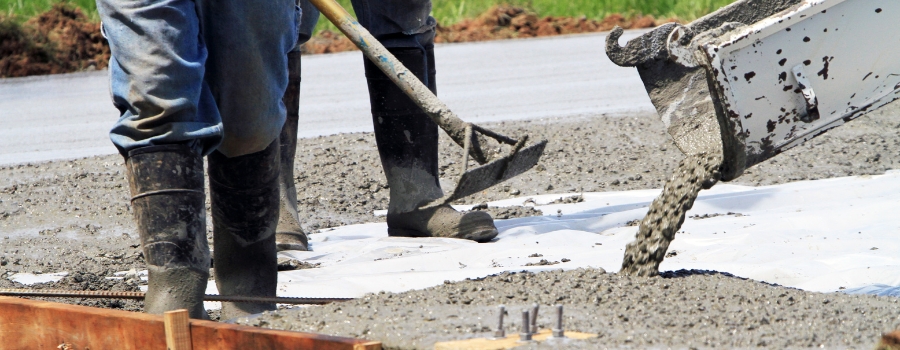 Construction workers pouring wet concrete using concrete bucket