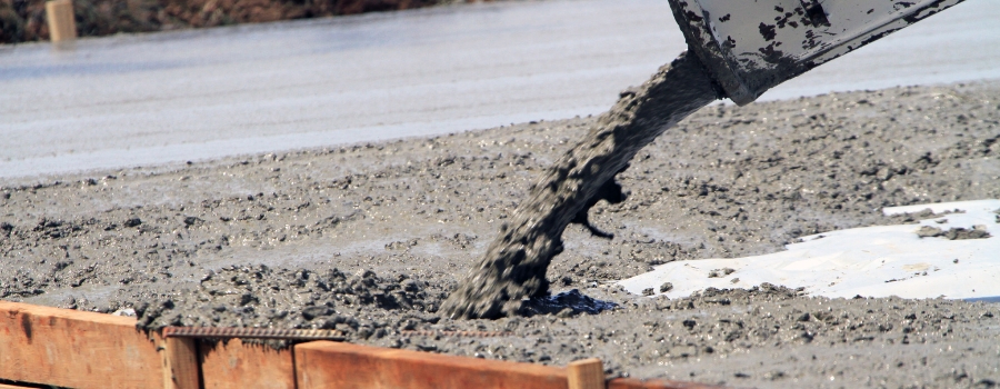 Construction workers pouring wet concrete using concrete bucket